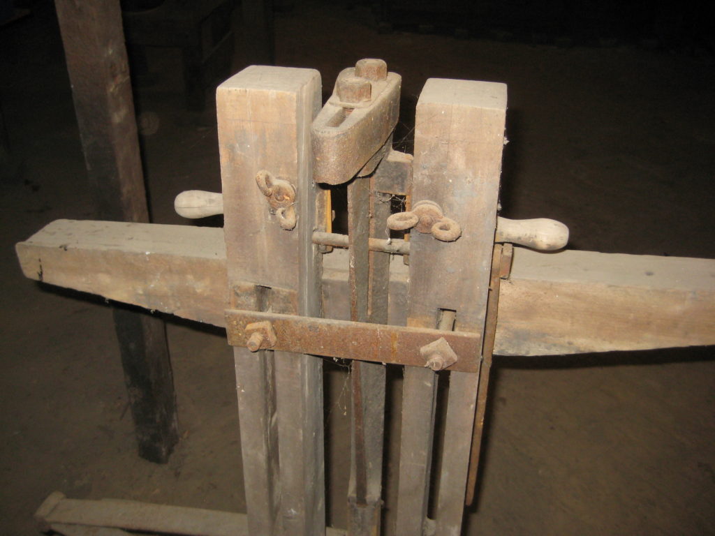 Unidentified wood device with metal parts, square nuts, and washer nuts, and hex nuts in basement of Melville House, medium closeup of top